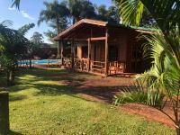 una pequeña casa de madera con un patio de césped en Cabañas Raíces Pampeanas, en Puerto Iguazú