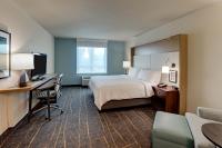 a hotel room with a bed and a desk with a computer at Holiday Inn Mobile Airport by IHG in Mobile