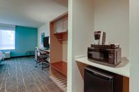 a room with a kitchen with a microwave and a desk at Holiday Inn Mobile Airport by IHG in Mobile
