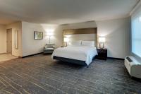a large hotel room with a bed and a chair at Holiday Inn Mobile Airport by IHG in Mobile