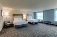 a hotel room with two beds and a chair at Holiday Inn Mobile Airport by IHG in Mobile