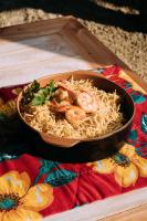 ポソス・デ・カルダスにあるPousada Trem Chicのテーブルの上にエビ入り麺のボウルが置かれている