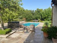 a backyard with a swimming pool and two chairs and a table at Mas des IRIS in Saint-Rémy-de-Provence