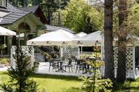 a patio with tables and chairs and white umbrellas at Aries Hotel & SPA Wisła in Wisła