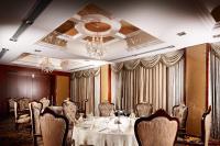 a dining room with a table and chairs and a chandelier at Beijing Hotel Minsk in Minsk