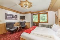 ein Hotelzimmer mit einem Bett und zwei Stühlen in der Unterkunft Naturhotel Lärchenhof in Ramsau am Dachstein