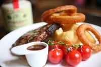 The Crown Hotel في وودبريدج: طبق من الطعام يحتوي على نقانق وحلقات بصل وطماطم