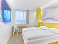 a bedroom with two beds and a table and a chair at prizeotel Hannover-City in Hannover