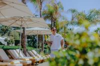 a man is standing in front of some chairs and umbrellas at Four Seasons Hotel in Limassol