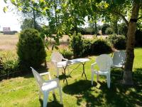 three chairs and a table in a yard with a tree at Entre forêts et prairies in Le Cercueil