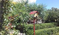 a bird house on a red pole in a garden at Apartment Lopar 28 in Lopar
