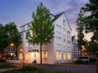 Un edificio blanco con un árbol delante. en Arthotel ANA Fleur, en Paderborn