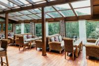 a conservatory with tables and chairs and windows at Hotel Troyer in Trojanovice