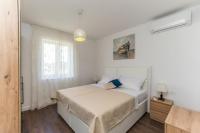 a white bedroom with a bed and a window at Holiday home Ivana - private pool in Privlaka