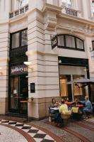 eine Gruppe von Menschen, die an Tischen vor einem Gebäude sitzen in der Unterkunft Novotel Den Haag City Centre in Den Haag