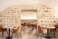Un restaurante con mesas y sillas y una pared de piedra. en Domaine et Château de Valinches, en Marols