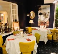 ein Esszimmer mit 2 Tischen und gelben Stühlen in der Unterkunft Hostellerie du Passeur - Hôtel & Restaurant - Climatisation et Piscine chauffée in Les Eyzies-de-Tayac