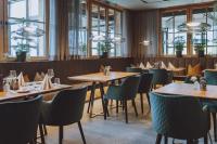 a restaurant with wooden tables and chairs and windows at Bergdorf Hotel Zaglgut in Kaprun