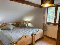 a bedroom with a bed with a wooden frame and a window at Ferme De La Prairie D Hergauchamps mit Sauna und Whirlpool in Sainte-Marie-aux-Mines
