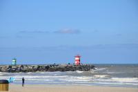 a person standing on a beach with a red and white lighthouse at Huize Maurits in The Hague