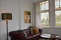 a living room with a brown leather couch and two windows at Huize Maurits in The Hague