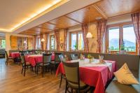 a restaurant with red tables and chairs and windows at Landhotel Schwarzenbach - Wellness & Spa in Rieden am Forggensee