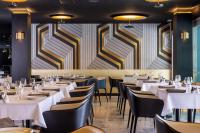 Un comedor con mesas blancas y sillas negras. en Hôtel Spa Restaurant Villa Castellane, en Gréoux-les-Bains