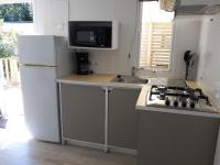 a kitchen with a stove and a sink and a refrigerator at Mobilhome 6 pers avec Clim in Saint-Georges-de-Didonne