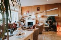 a living room with tables and chairs and a fireplace at Hôtel Aux Tamaris - Vue Mer in Roscoff