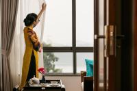 ハノイにあるLucien Hanoi Lakeside Hotel & Rooftopのホテルの窓を開ける女性