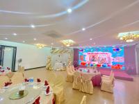 a party hall with tables and chairs and a stage at White Hotel in Hà Tĩnh