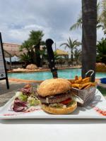un sandwich et des frites dans une assiette à côté d'une piscine dans l'établissement Résidence & SPA Marina d'Arone, à Piana