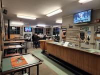 Un restaurante con un bar con gente sentada en mesas. en Whitehorse Inn, en Palmerston North