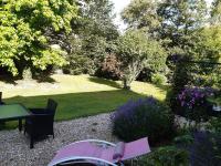 a garden with a table and chairs and flowers at les orchidees sauvages in Touffreville-la-Corbeline