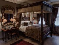 a bedroom with a canopy bed with a table and a chair at The Rookery in London