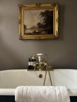 a bathroom with a bath tub with a painting on the wall at The Rookery in London