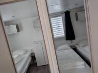 a small room with two beds and a mirror at Chalet Berg 616 op vakantiepark Bergumermeer aan het water in Suameer