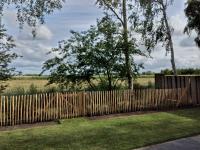 a wooden fence with a field behind it at Chalet Berg 616 op vakantiepark Bergumermeer aan het water in Suameer