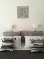 Cama blanca con almohadas blancas y negras en Rodia Studios &amp; Apartments, en Parikia