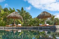una piscina con sillas y sombrillas y árboles en Hotel Hare Uta, en Hanga Roa