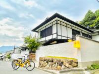 Una bicicleta amarilla estacionada frente a una casa en Miyajima Guest House Mikuniya, en Miyajima