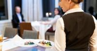 una mujer sosteniendo un plato de comida en una mesa en Oberwaid - Das Hotel., en St. Gallen
