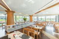 a restaurant with tables and chairs and windows at Na Tree Tara Riverside Resort Amphawa Damnoensaduak in Amphawa