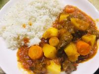 a white plate of food with rice and stew at Pole Pole Beach House in Watamu