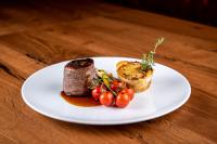 un plato blanco con carne y verduras en una mesa en Hotel B&B Feldmessner, en Brunico