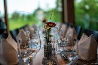 una mesa con gafas y un jarrón con una flor. en Hotel Rössli Tufertschwil, en Lütisburg