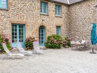 a group of chairs and an umbrella in front of a building at Holiday Home La Vallée by Interhome in Cancale