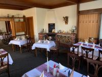 uma sala de jantar com mesas brancas e cadeiras de madeira em Forsthaus Siehdichum em Dammendorf