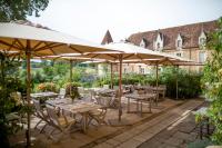 a patio with tables and chairs under umbrellas at Domaine des Etangs, Auberge Collection in Massignac