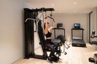 a woman is in a gym on a exercise bike at 6717 Nature Hôtel &amp; Spa Le Clos des Délices in Ottrott